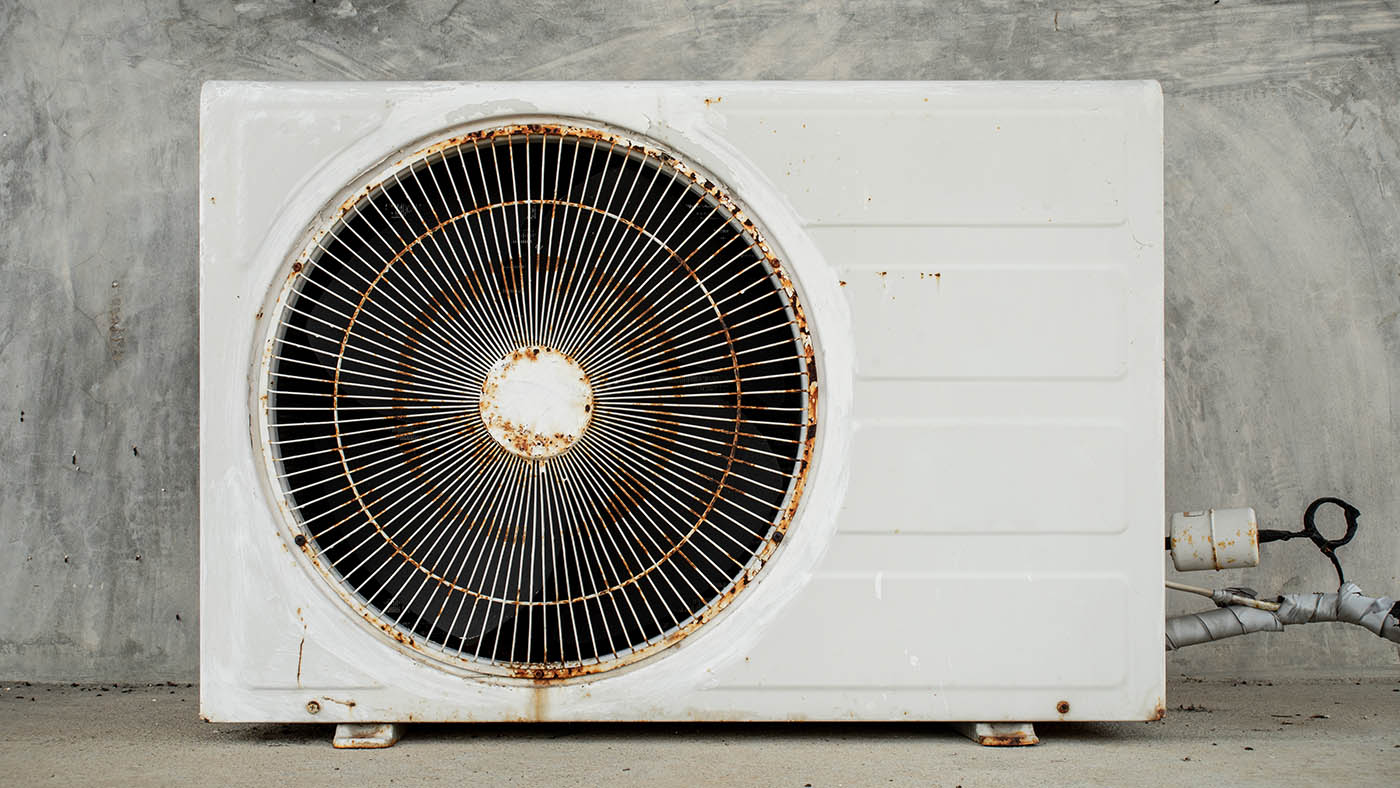 Old, worn-out air-conditioning condenser unit before replacement